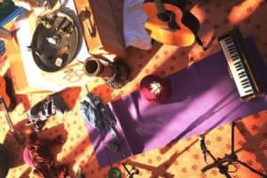 2 Gitarren, ein Harmonium, eine Tromme, ein Mikrofon und eine Trommel sind wild verteilt um eine Yogamatte herum.